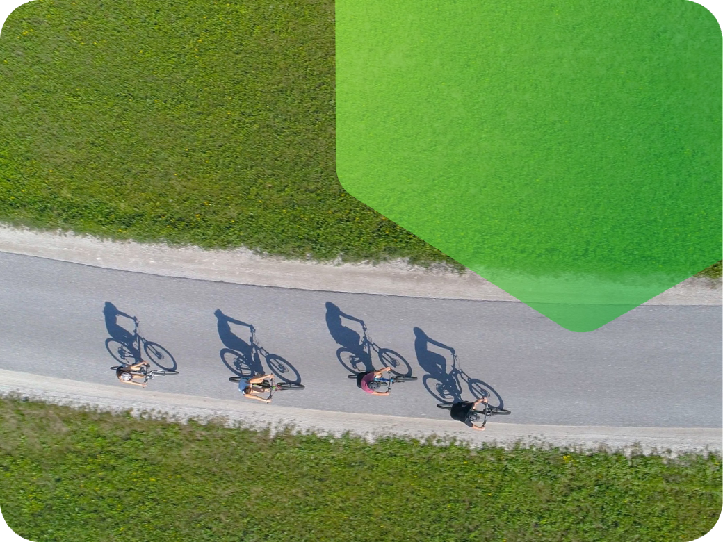 Cyclists on a road surrounded by grass on a sunny day